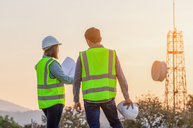 Professional team Engineer managers workers working outdoors with telecommunication antenna and sunset background.